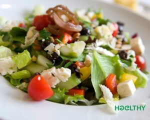 A bowl of Mediterranean salad with fresh vegetables, olives, and feta cheese